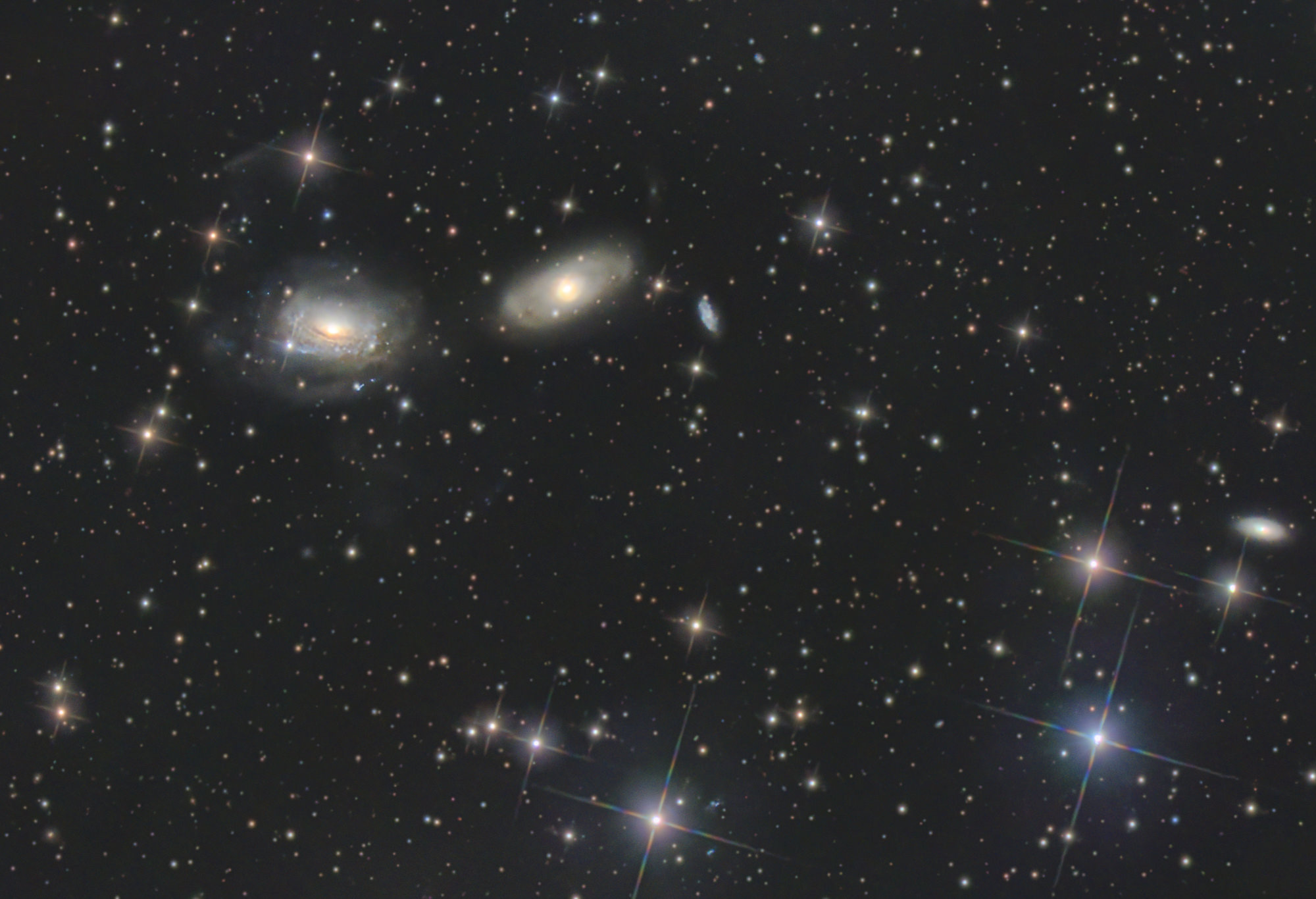 Die gewundenen Spiralarme von NGC 3169 (links) wurden durch die gravitative Wechselwirkung mit der benachbarten Galaxie NGC 3166 zu ausladenden Gezeitenschweifen herausgezogen. Die beiden Galaxien werden am Ende zu einer verschmelzen.